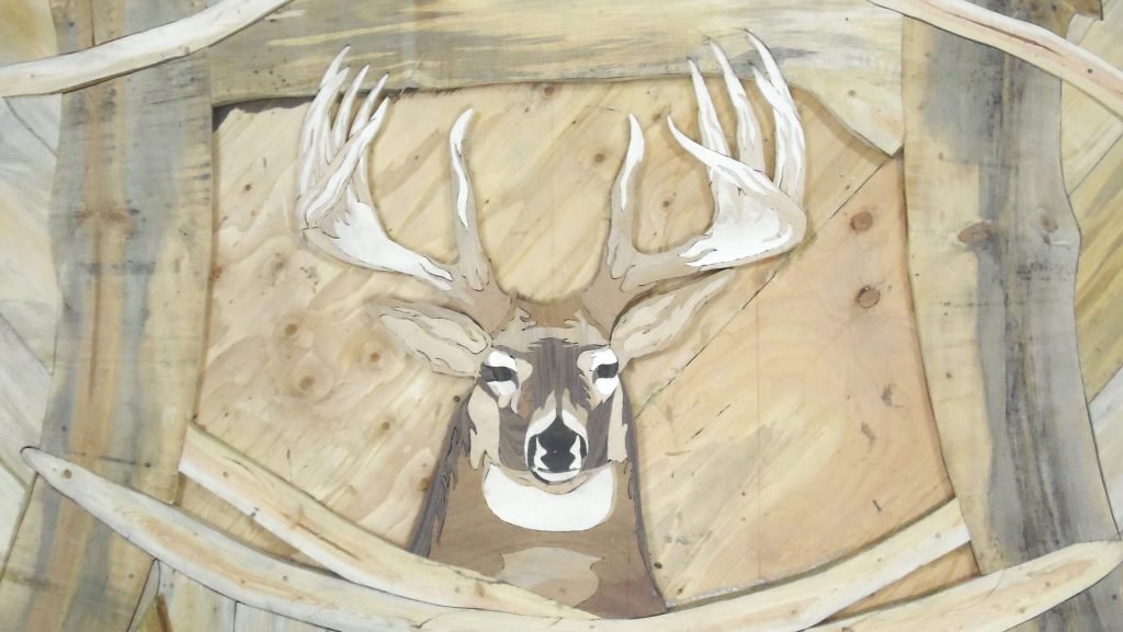 A male deer being crafted into a custom hardwood art floor. 