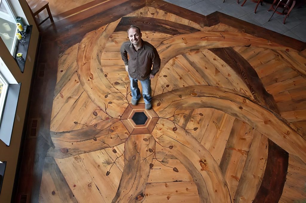 Tom Ourada stands on the Blue Pine Swirl custom hardwood art floor. 